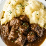 Delicious Beef Tips Recipe with Rich Gravy (Easy & Hearty) 2 Tender beef tips with rich brown gravy served with mashed potatoes on a white plate.