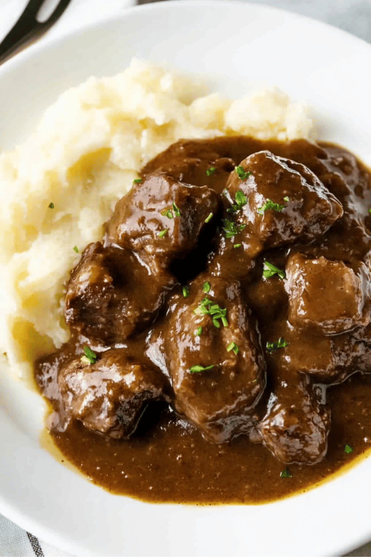 Close-Up of Beef Tips in Gravy Close-up of juicy beef tips smothered in homemade gravy served over mashed potatoes.