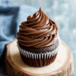 🍫 Creamy Chocolate Frosting Recipe: A Rich, Velvety Classic 2 Chocolate cupcake topped with rich, swirled chocolate frosting on a rustic wood slice.
