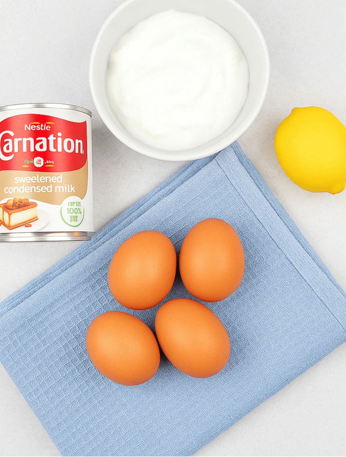 Ingredients for cloud cake recipe including eggs, yogurt, lemon, and condensed milk