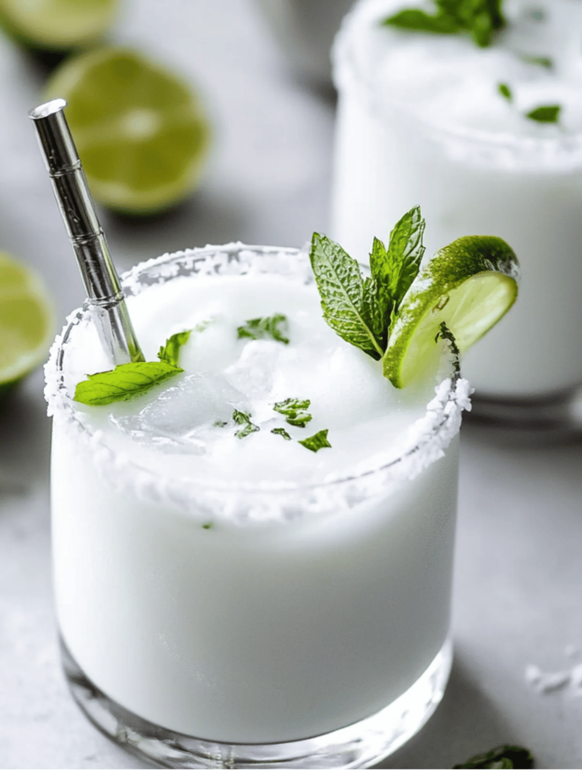 Classic Coconut Mojito on Ice with Lime and Mint Icy Coconut Mojito cocktail with mint, lime slice, and salt rim in a short glass
