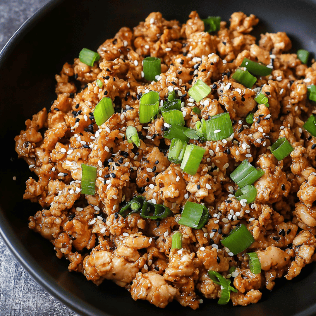 Savory Sesame Ground Chicken with Green Onions Ground chicken with sesame glaze and green onions in a black bowl
