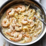 🥄 Creamy & Irresistible: The Ultimate Shrimp Alfredo Recipe 2 Creamy Shrimp Alfredo pasta in a skillet with fettuccine and fresh herbs