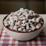 Puppy Chow Recipe: The Addictive Snack You’ll Crave Every Time 2 lose-up of puppy chow in deep navy bowl on red towel