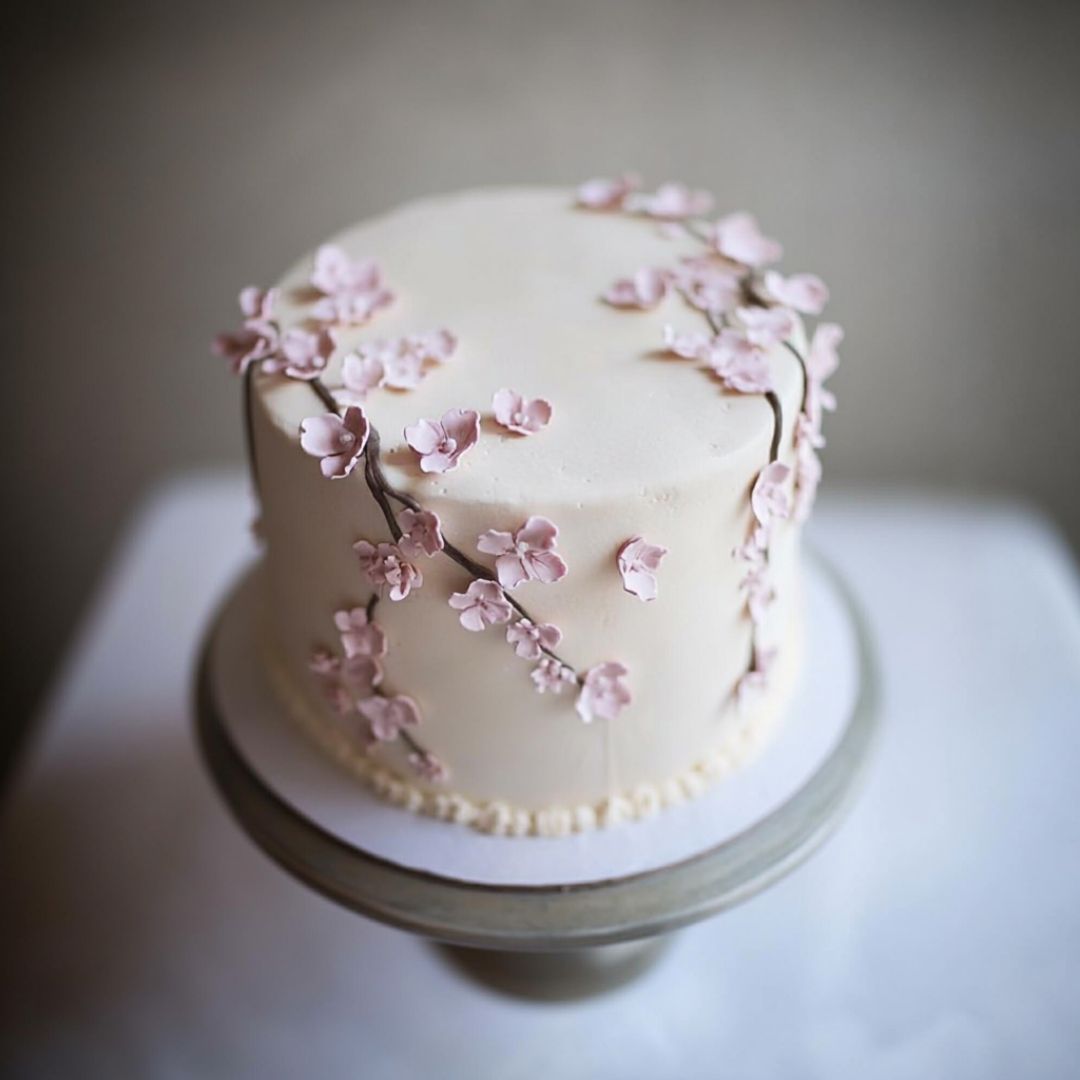 Vertical Sakura Cake with Climbing Blossoms Tall sakura cake with small pink blossoms winding up the sides